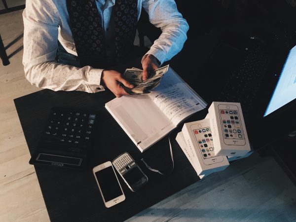 person-counting-money-with-smartphones-in-front-on-desk-210990